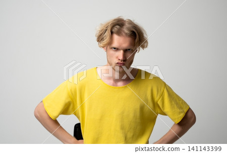 Young man showing anger and frustration with hands on hips, pouting face and furrowed brow, conveying strong negative emotions, annoyance or disapproval a bad mood Young man showing anger and frustration with hands on hips, pouting face and furrowed brow, conveying strong negative emotions, annoyance or disapproval a bad mood 141143399