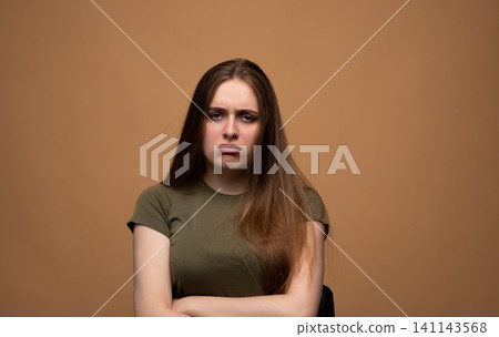 Young woman showing negative emotion, pouting and looking frustrated with arms crossed in a studio setting Young woman showing negative emotion, pouting and looking frustrated with arms crossed in a studio setting 141143568
