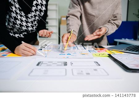 UI developer team brainstorming on their project with laptop, smartphone and digital tablet. UI developer team brainstorming on their project with laptop, smartphone and digital tablet. 141143778