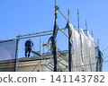 Craftsmen performing roof repair work on temporary scaffolding. Craftsmen performing roof repair work on temporary scaffolding. 141143782