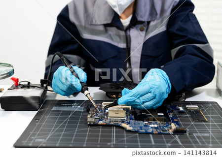 Closeup of expert soldering a green PCB board using precision tools. Ideal for electronics, circuit repair, engineering 141143814