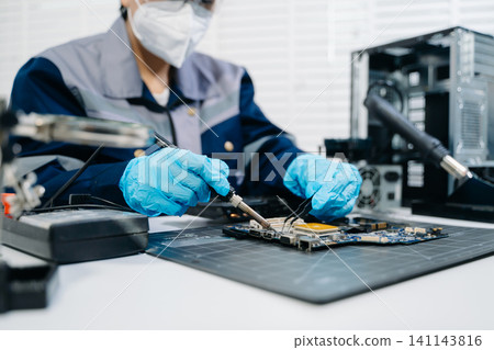Closeup of expert soldering a green PCB board using precision tools. Ideal for electronics, circuit repair, engineering 141143816