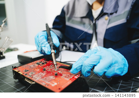 Professional technician repairing a graphics card PCB using soldering equipment. Ideal for technology, electronics repair, engineering and IT service concepts. Professional technician repairing a graphics card PCB using soldering equipment. Ideal for technology, electronics repair, engineering and IT service concepts. 141143895