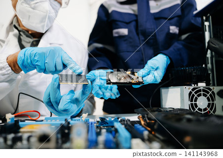 Technicians repairing computer hardware, testing components and upgrading PC systems. Technology service, electronics engineering and IT support concept. Technicians repairing computer hardware, testing components and upgrading PC systems. Technology service, electronics engineering and IT support concept. 141143968