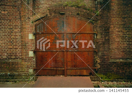Rusty iron door and red brick warehouse exterior wall: Background material for a ruined, retro-style building. Rusty iron door and red brick warehouse exterior wall: Background material for a ruined, retro-style building. 141145455