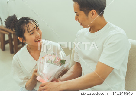 女人接過花束,對著男人微笑。 女人接過花束,對著男人微笑。 141146849
