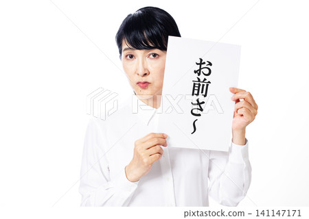 一位身穿白襯衫的中年婦女拿著一張寫著「嘿，你」的紙條，目不轉睛地盯著鏡頭。 141147171