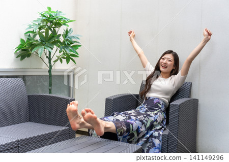 一位年輕女子在短租房的露臺上伸展身體放鬆。 一位年輕女子在短租房的露臺上伸展身體放鬆。 141149296