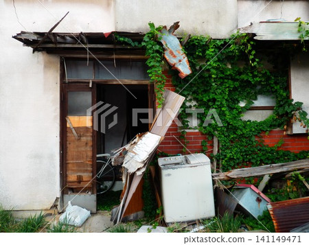 The entrance to an abandoned house where garbage and plants have been left behind. The entrance to an abandoned house where garbage and plants have been left behind. 141149471