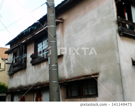 Windows and utility poles of an aging wooden house 141149473