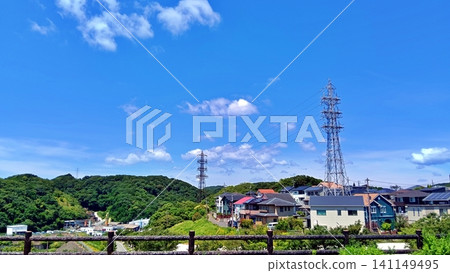 A summer scene of a residential area with a blue sky and a transmission tower. A summer scene of a residential area with a blue sky and a transmission tower. 141149495