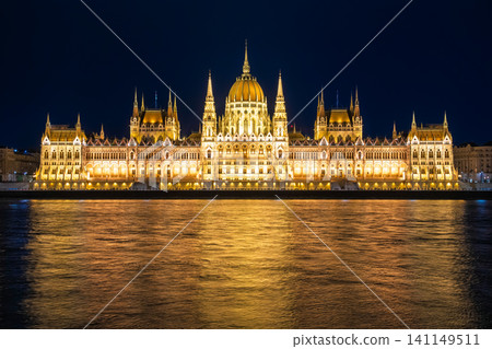 A fantastical night view of the Hungarian Parliament building reflected in the golden light on the surface of the Danube River in Budapest, Hungary. A fantastical night view of the Hungarian Parliament building reflected in the golden light on the surface of the Danube River in Budapest, Hungary. 141149511