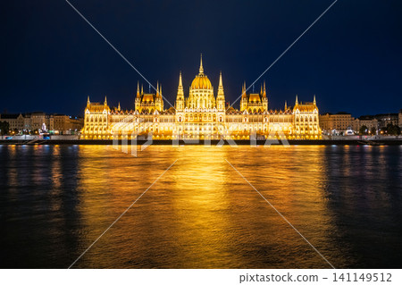 A fantastical night view of the Hungarian Parliament building reflected in the golden light on the surface of the Danube River in Budapest, Hungary. A fantastical night view of the Hungarian Parliament building reflected in the golden light on the surface of the Danube River in Budapest, Hungary. 141149512