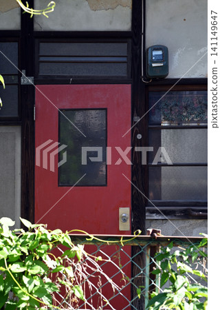 The red door of an old apartment building 141149647