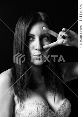 Woman portrait in black and white with retro style. Lady showing peace sign gesture on dark background. Artistic analog photography with film grain Woman portrait in black and white with retro style. Lady showing peace sign gesture on dark background. Artistic analog photography with film grain 141150720