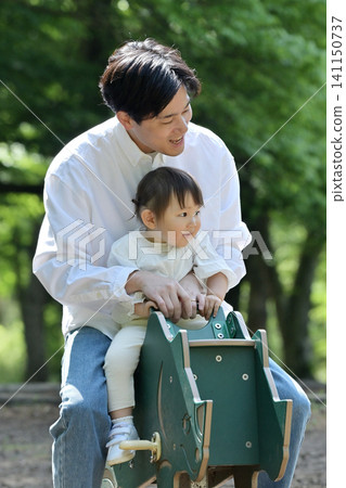 一對父女在公園玩春季遊樂設施。 一對父女在公園玩春季遊樂設施。 141150737