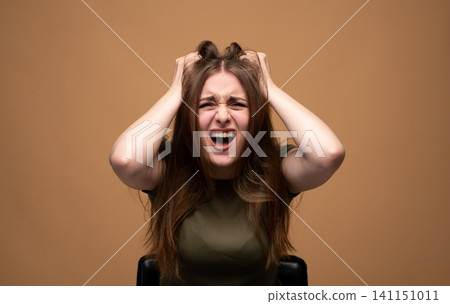 Young woman stressing out, screaming with hands clutching her hair, expressing frustration, anxiety, and extreme anger Young woman stressing out, screaming with hands clutching her hair, expressing frustration, anxiety, and extreme anger 141151011