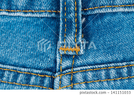 Blue denim jeans texture with belt loop and orange stitching close up Blue denim jeans texture with belt loop and orange stitching close up 141151033