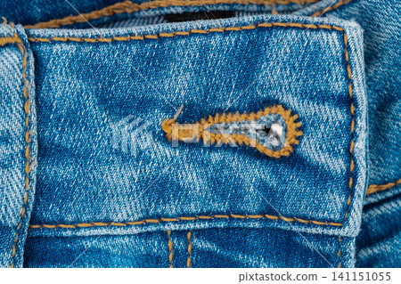 Denim fabric closeup with buttonhole and orange stitching Denim fabric closeup with buttonhole and orange stitching 141151055