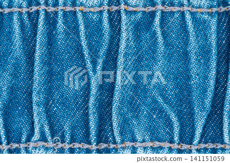 Closeup of blue denim fabric with stitched seams and textured weave pattern 141151059