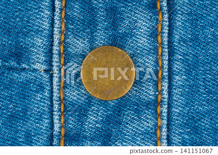 Blue denim fabric with brass button and yellow stitching closeup Blue denim fabric with brass button and yellow stitching closeup 141151067