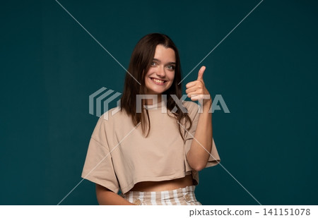 Happy young woman giving thumbs up, smiling and showing approval, acceptance or success gesture against a dark background Happy young woman giving thumbs up, smiling and showing approval, acceptance or success gesture against a dark background 141151078