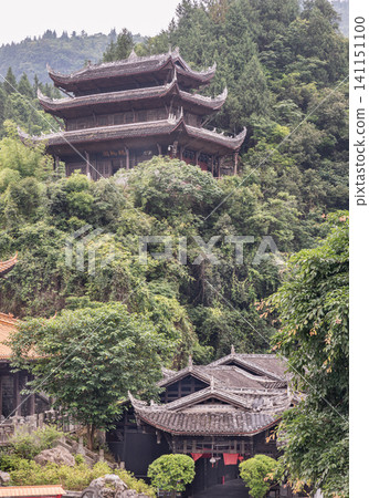 A multi-tiered wooden pavilion sits dramatically atop a lush mountainside, showcasing the timeless beauty of traditional design. Below, smaller structures with intricate tiled roofs and elegant, A multi-tiered wooden pavilion sits dramatically atop a lush mountainside, showcasing the timeless beauty of traditional design. Below, smaller structures with intricate tiled roofs and elegant, 141151100