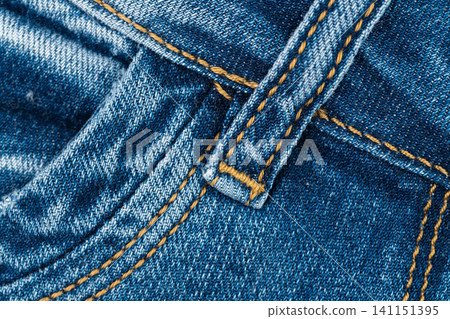 Closeup of blue denim fabric with yellow stitching and pocket detail Closeup of blue denim fabric with yellow stitching and pocket detail 141151395