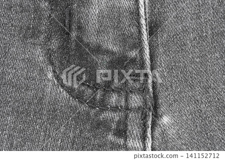 Close up view of black denim fabric with stitched seam and fly edge. Textured cotton material for jeans background. Fashion apparel surface detail for clothing industry design concept Close up view of black denim fabric with stitched seam and fly edge. Textured cotton material for jeans background. Fashion apparel surface detail for clothing industry design concept 141152712