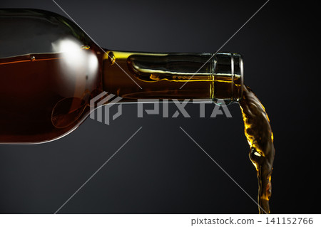 White wine of a rich amber color pours out of the bottle. White wine of a rich amber color pours out of the bottle. 141152766