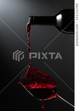 Red wine of rich color being poured from a bottle into a glass. Red wine of rich color being poured from a bottle into a glass. 141152769