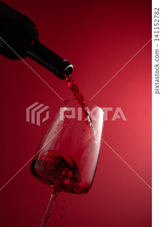Pouring red wine from a bottle into a glass. Pouring red wine from a bottle into a glass. 141152782