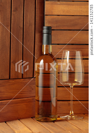 Bottle and glass of white wine on a wooden background. Bottle and glass of white wine on a wooden background. 141152785