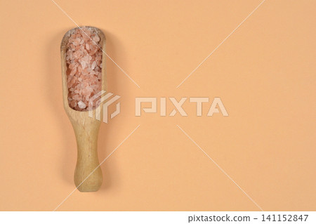 Pink Himalayan Salt in Wooden Scoop on Peach Background Pink Himalayan Salt in Wooden Scoop on Peach Background 141152847