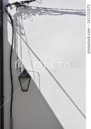 Vintage street lamp and tangled cables on a white wall facade Vintage street lamp and tangled cables on a white wall facade 141152872