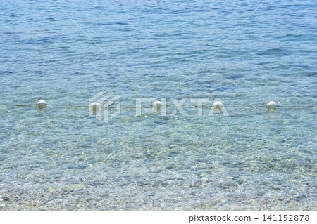 White buoys on a safety barrier rope in clear blue sea water White buoys on a safety barrier rope in clear blue sea water 141152878