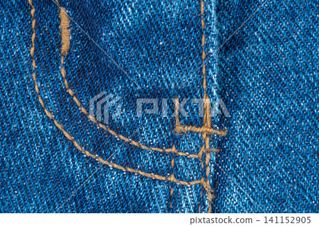 Closeup of blue denim fabric with orange thread stitching. Detail of trousers fly seam. Texture of jeans material for clothing design and textile industry background concept Closeup of blue denim fabric with orange thread stitching. Detail of trousers fly seam. Texture of jeans material for clothing design and textile industry background concept 141152905