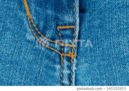 Blue denim jeans texture with close up fly stitch detail. Fabric pattern of cotton material for fashion clothing industry. Textile background with orange thread seam for apparel Blue denim jeans texture with close up fly stitch detail. Fabric pattern of cotton material for fashion clothing industry. Textile background with orange thread seam for apparel 141152913