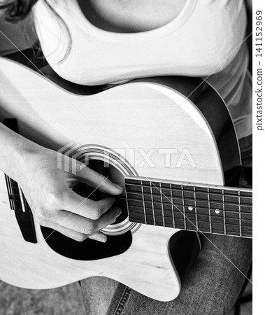 Woman guitarist playing guitar. Closeup of fingers on strings. Black and white retro vintage photo Woman guitarist playing guitar. Closeup of fingers on strings. Black and white retro vintage photo 141152969