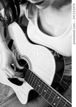 Woman playing acoustic guitar. Closeup of musician fingers on strings. Black and white vintage style Woman playing acoustic guitar. Closeup of musician fingers on strings. Black and white vintage style 141152970