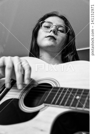 Young woman playing guitar. Portrait of musician with instrument. Black and white vintage style Young woman playing guitar. Portrait of musician with instrument. Black and white vintage style 141152971