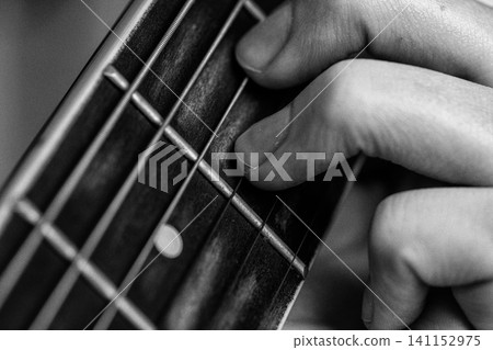 Musician hand playing acoustic guitar string. Closeup fingers on fretboard. Monochrome retro style Musician hand playing acoustic guitar string. Closeup fingers on fretboard. Monochrome retro style 141152975
