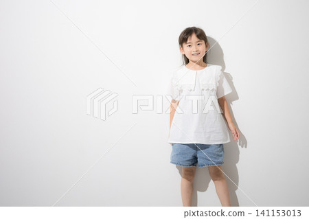 A smiling Japanese girl standing in front of a white background; full-body portrait and copy space. A smiling Japanese girl standing in front of a white background; full-body portrait and copy space. 141153013