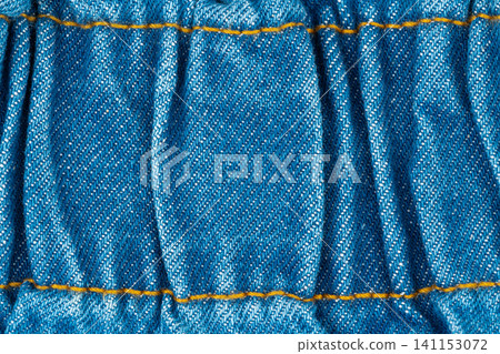 Blue denim fabric texture with golden stitching. Close up of jeans textile macro detail. Material background with folds and seam. Fashion clothing industry pattern for garment design Blue denim fabric texture with golden stitching. Close up of jeans textile macro detail. Material background with folds and seam. Fashion clothing industry pattern for garment design 141153072