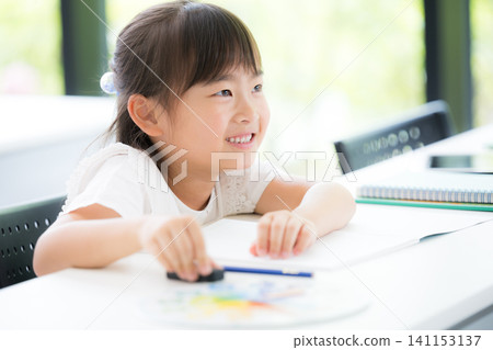 A kindergarten or elementary school girl concentrating on studying while looking at the blackboard in the classroom; attending cram school or regular school; preparing for exams or studying. A kindergarten or elementary school girl concentrating on studying while looking at the blackboard in the classroom; attending cram school or regular school; preparing for exams or studying. 141153137