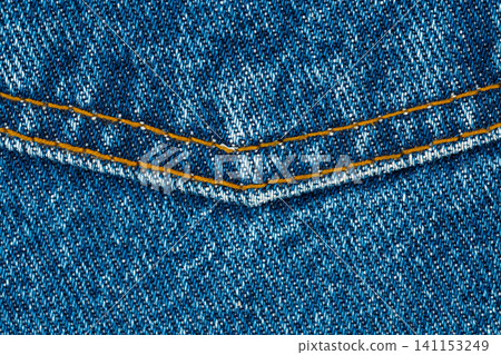 Blue denim fabric with yellow stitching detail closeup Blue denim fabric with yellow stitching detail closeup 141153249