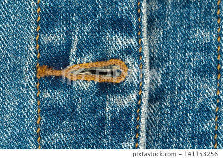 Blue denim fabric texture with buttonhole and orange stitching Blue denim fabric texture with buttonhole and orange stitching 141153256