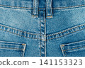 Blue jeans texture with back pocket detail. Close up of denim fabric with yellow stitching and belt loops 141153323