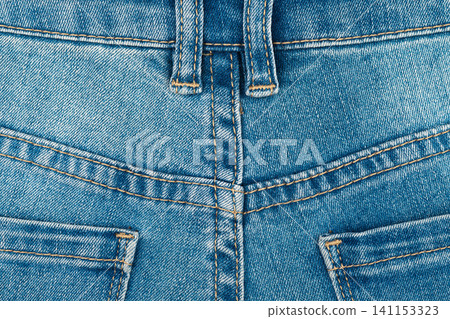 Blue jeans texture with back pocket detail. Close up of denim fabric with yellow stitching and belt loops Blue jeans texture with back pocket detail. Close up of denim fabric with yellow stitching and belt loops 141153323