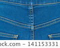 Blue denim jeans texture background with yellow stitching. Closeup jeans fabric showing seam detail 141153331